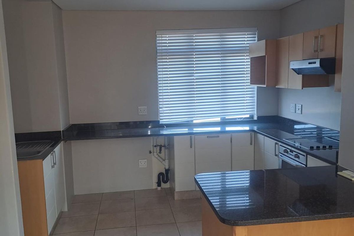 A functional kitchen featuring granite countertops, built-in oven, extractor fan, and ample cabinetry. The space is currently vacant and ready for personalization.