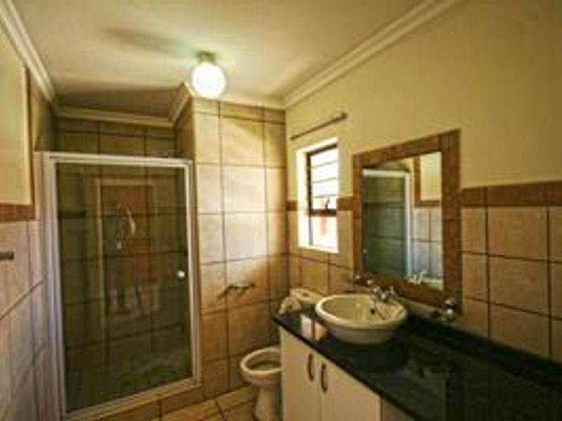 A functional bathroom featuring a shower enclosure, vanity with granite countertop, vessel sink, and tiled finishes throughout.