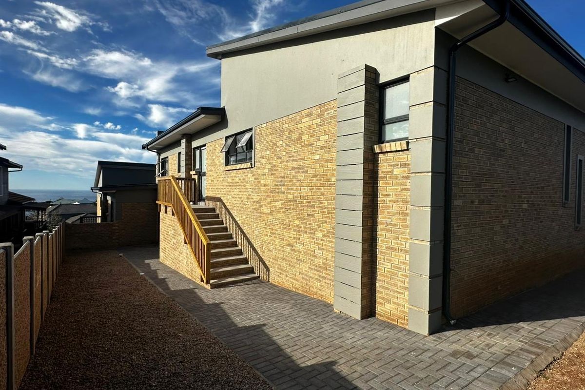 Rear exterior view of the cluster property featuring a paved courtyard, brick facade, and an external staircase leading to an upper level entrance.
