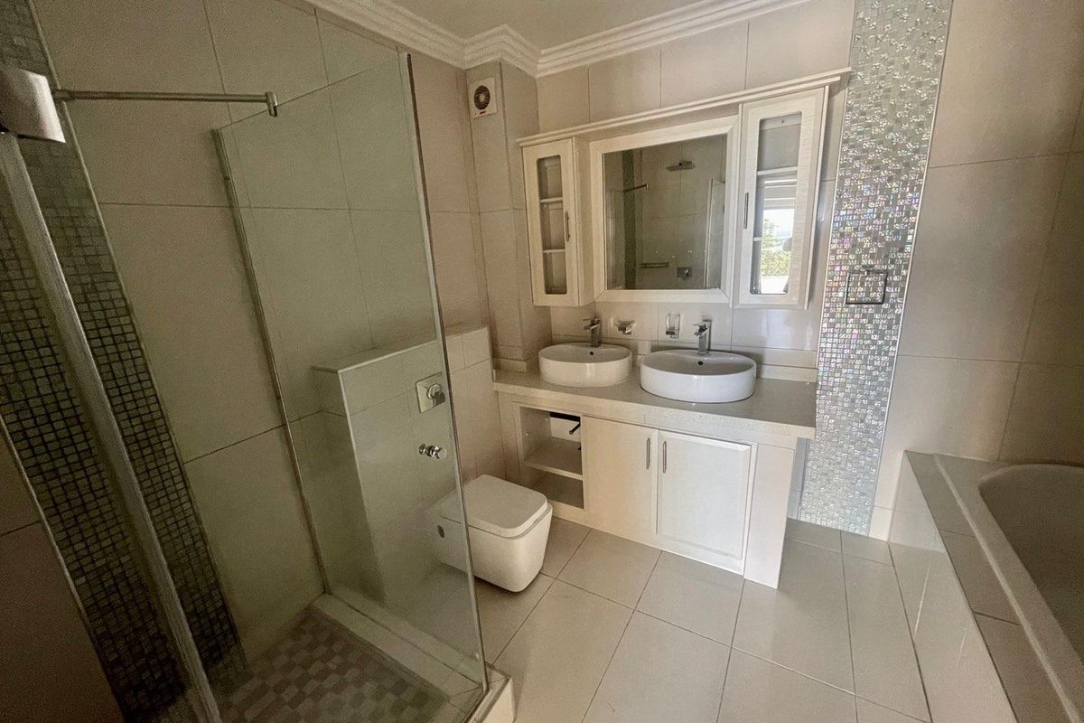 Modern bathroom featuring a glass-enclosed shower, a separate bathtub, and a double vanity with vessel sinks and built-in cabinetry.