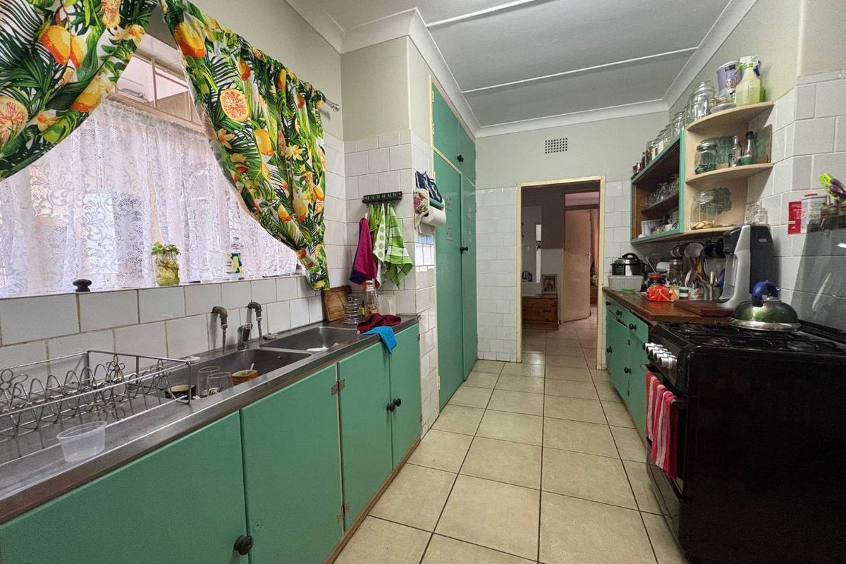 A functional galley-style kitchen featuring original cabinetry, tiled splashbacks, and ceramic flooring, offering significant potential for a modern renovation.