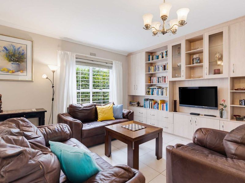 A comfortable living room featuring extensive built-in cabinetry, tiled flooring, and a classic chandelier, providing ample storage and a functional layout.