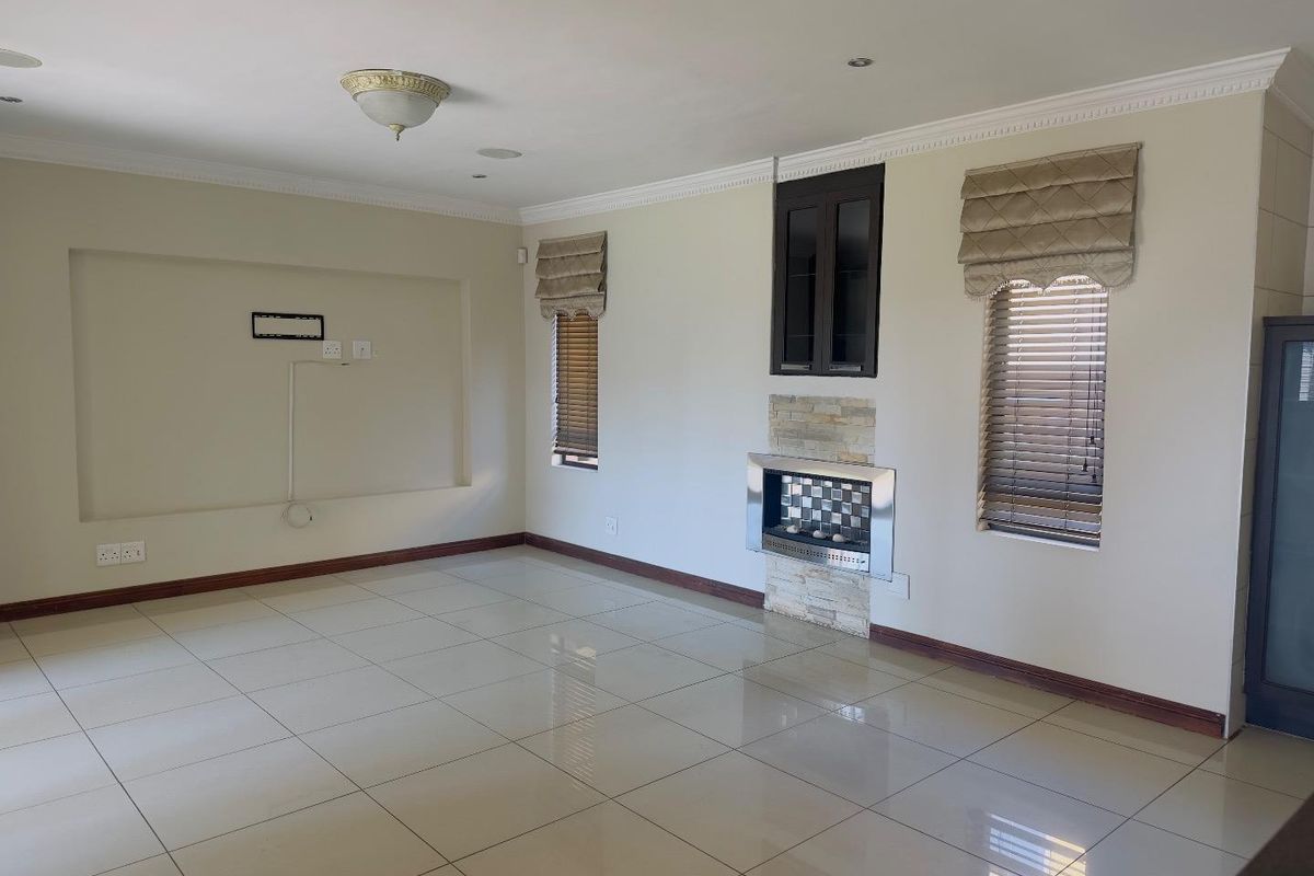 Spacious living room featuring tiled flooring, a built-in fireplace with stone cladding, and recessed wall space for media equipment.