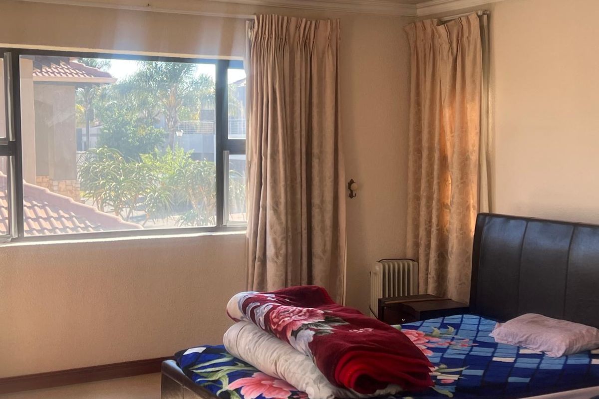 A bedroom featuring large windows with aluminium frames, neutral wall finishes, and standard skirting boards, offering natural light and a view of the exterior.