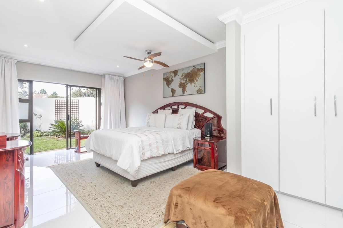 Spacious bedroom featuring a recessed ceiling tray, built-in cupboards, and sliding glass doors providing direct access to the garden.