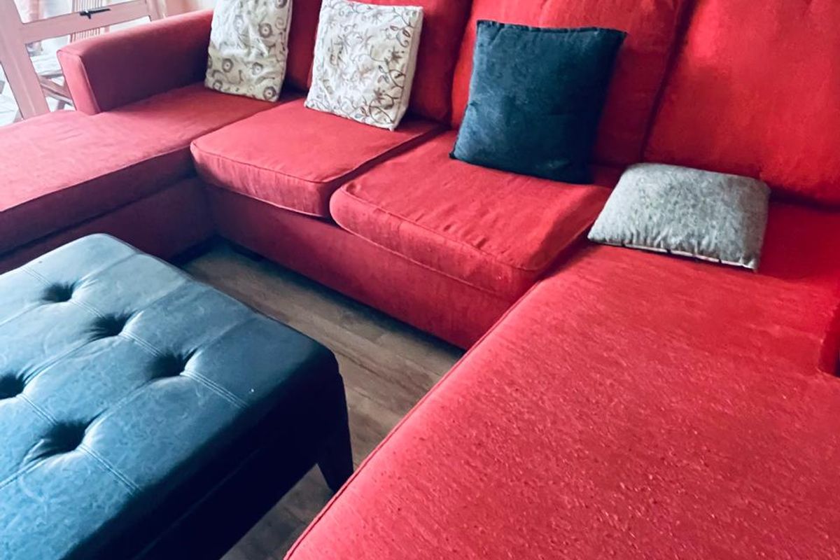 A living room area featuring laminate flooring and a large window providing natural light.