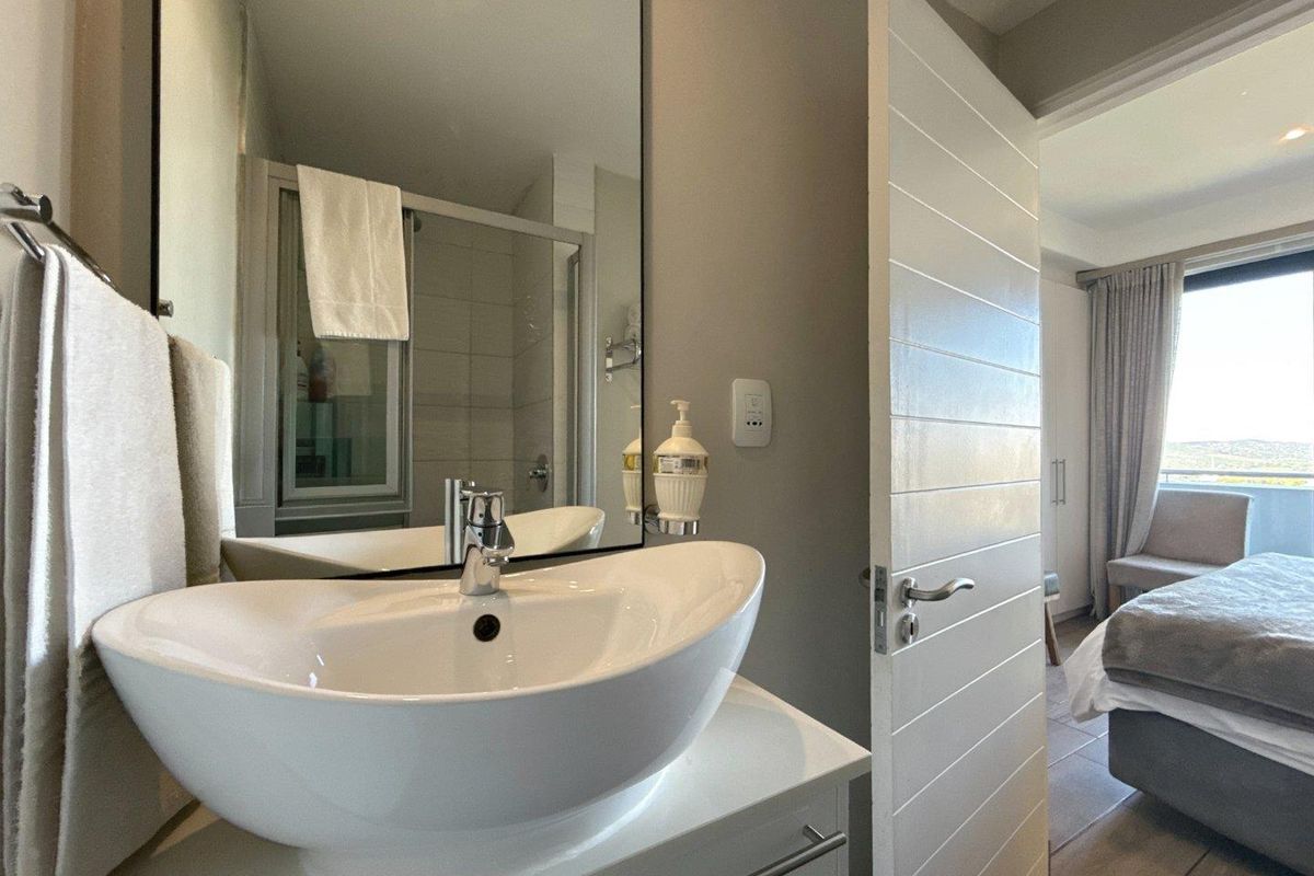 Modern bathroom featuring a contemporary vessel sink, vanity cabinet, large wall-mounted mirror, and a glass-enclosed shower unit.