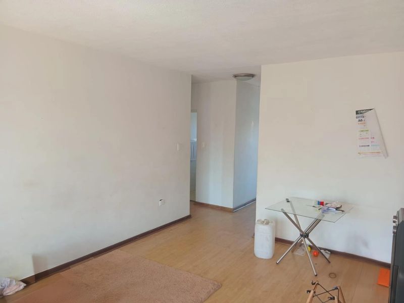 An empty living area featuring laminate flooring and neutral walls, providing a blank canvas for interior design and personalization.