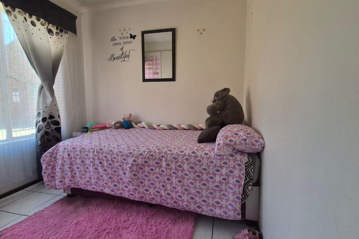 A functional bedroom featuring tiled flooring and a large window, providing natural light and a neutral base for interior design updates.