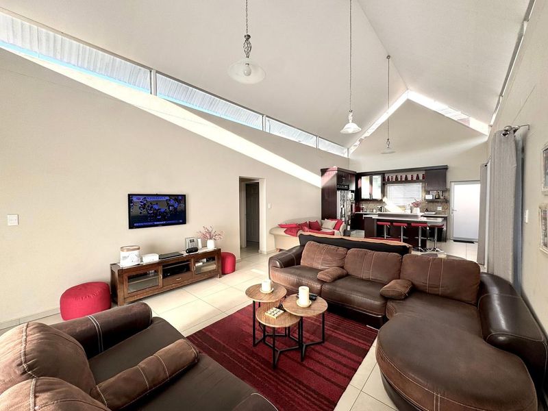 Spacious open-plan living and kitchen area featuring high vaulted ceilings, clerestory windows for natural light, and modern tiled flooring throughout.