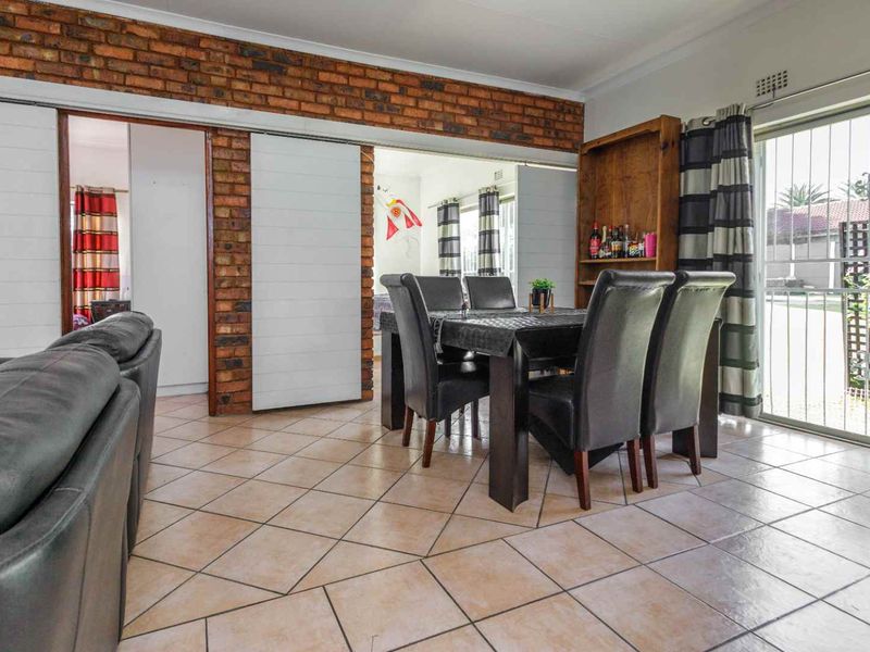 Open plan living and dining area featuring exposed brick accents, ceramic floor tiles, and sliding door access to the exterior.
