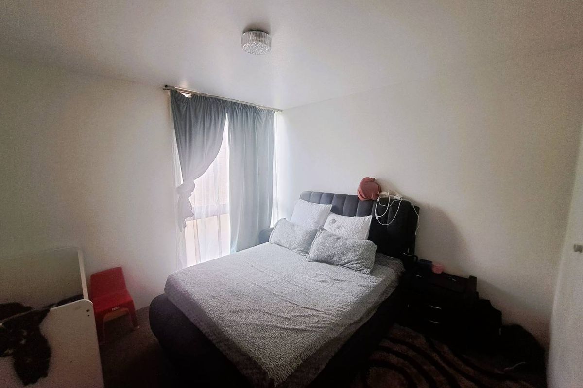 A standard bedroom featuring a window with curtains and a central ceiling light fixture.