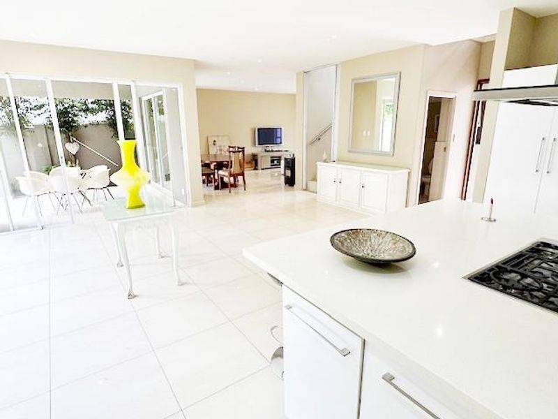 Spacious open-plan living area featuring a modern kitchen with a gas hob, sleek white cabinetry, and large sliding doors leading to the patio.
