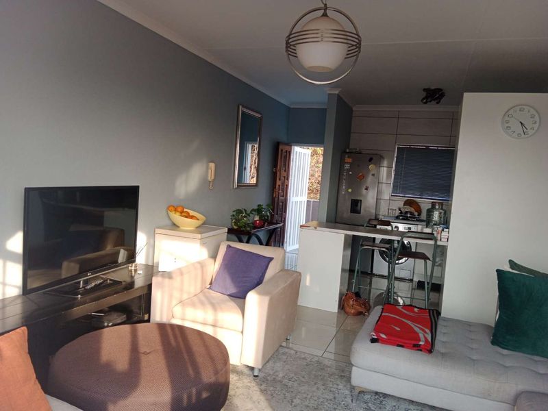 An open-plan living and kitchen area featuring tiled floors, a breakfast bar, and direct access to an exterior entrance.