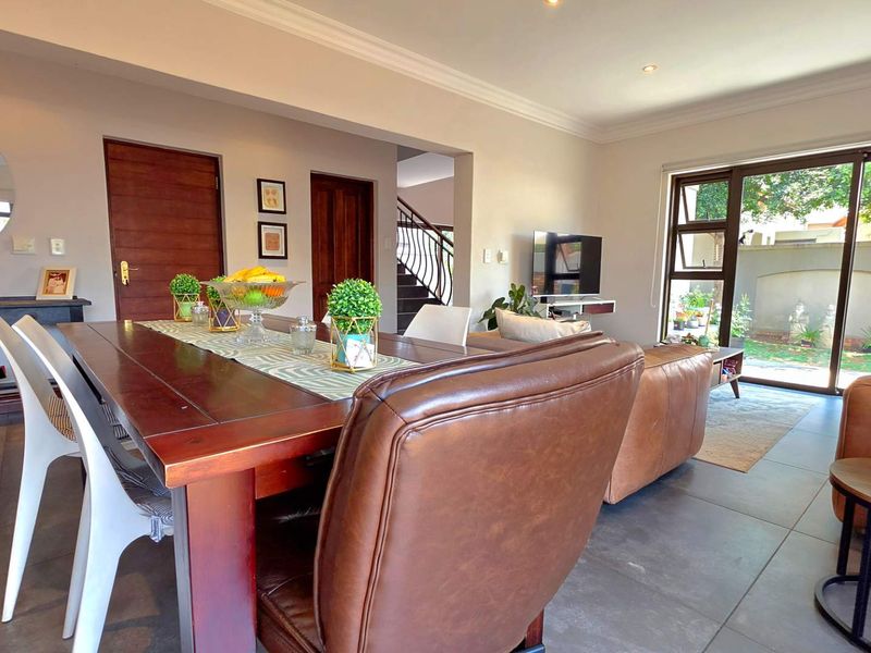 Spacious open-plan living and dining area featuring large format floor tiles, recessed lighting, and sliding glass doors providing seamless access to the outdoor space.