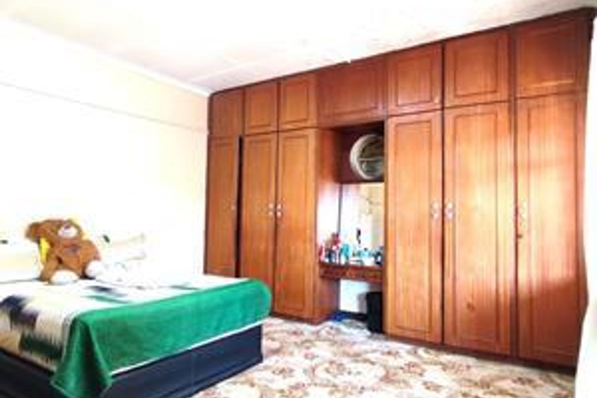 Bedroom featuring extensive floor-to-ceiling built-in wooden cabinetry with an integrated vanity unit.