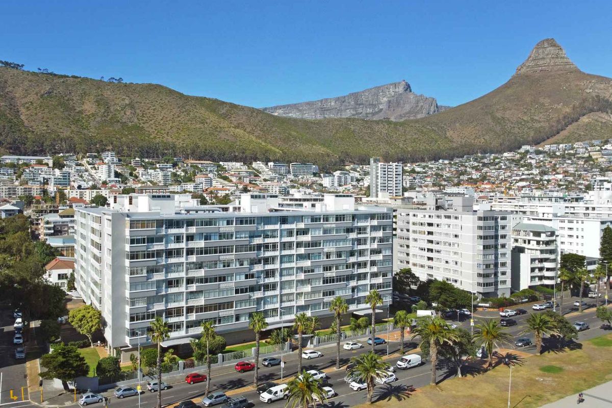 Aerial view of a multi-story apartment complex situated in a suburban area with mountain views in the background.