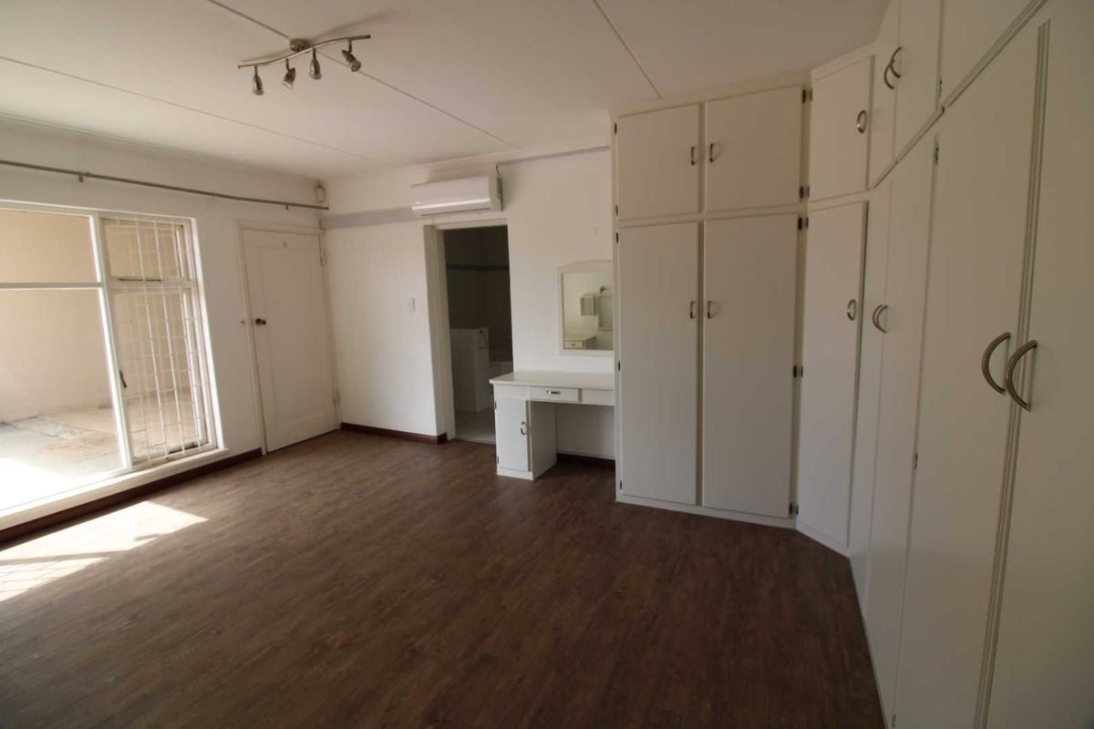 Spacious bedroom featuring built-in wardrobes, a vanity unit, split-system air conditioning, and direct access to an outdoor balcony area.