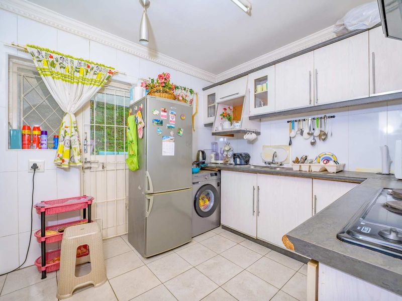 Functional kitchen featuring built-in cabinetry, tiled splashbacks, and direct access to the exterior via a security gate.
