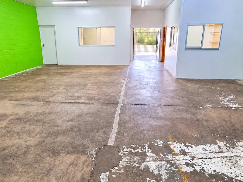 Open-plan industrial utility space featuring concrete flooring, internal partitioning, and fluorescent lighting, suitable for workshop or storage use.
