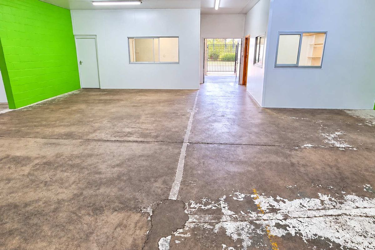 Open-plan industrial utility space featuring concrete flooring, internal partitioning, and fluorescent lighting, suitable for workshop or storage use.