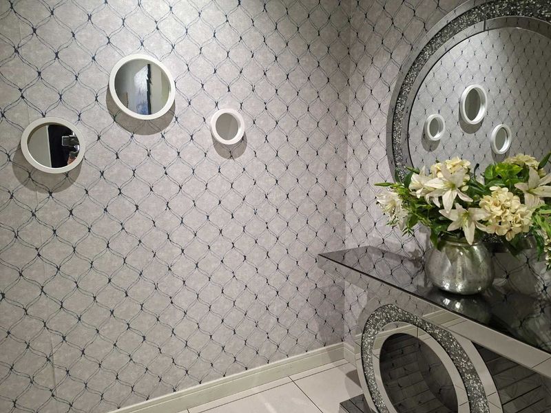 A well-maintained hallway featuring decorative patterned wallpaper, tiled flooring, and clean skirting boards, creating a bright and welcoming entrance area.