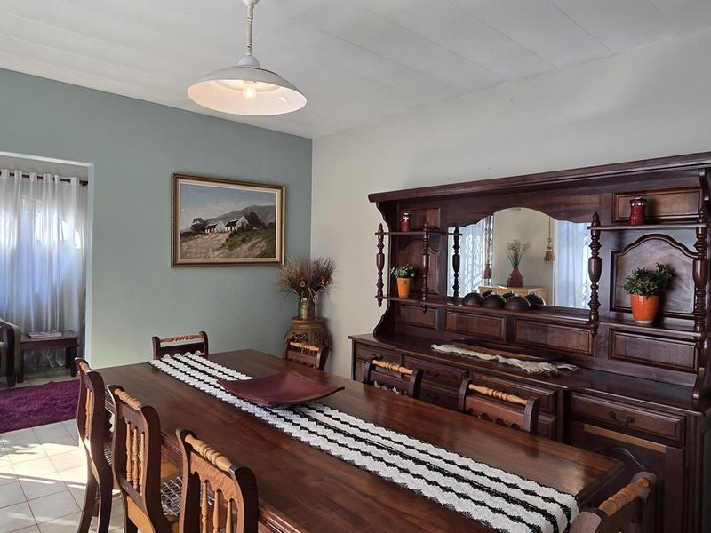 A dining room featuring tiled flooring and a central pendant light, with an open transition to an adjacent living area.