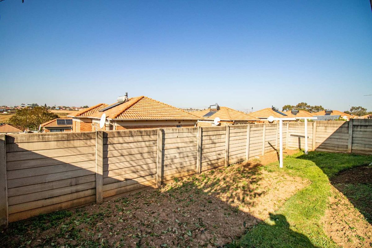 A view of the rear garden area featuring a precast concrete boundary wall and a metal clothes drying line.