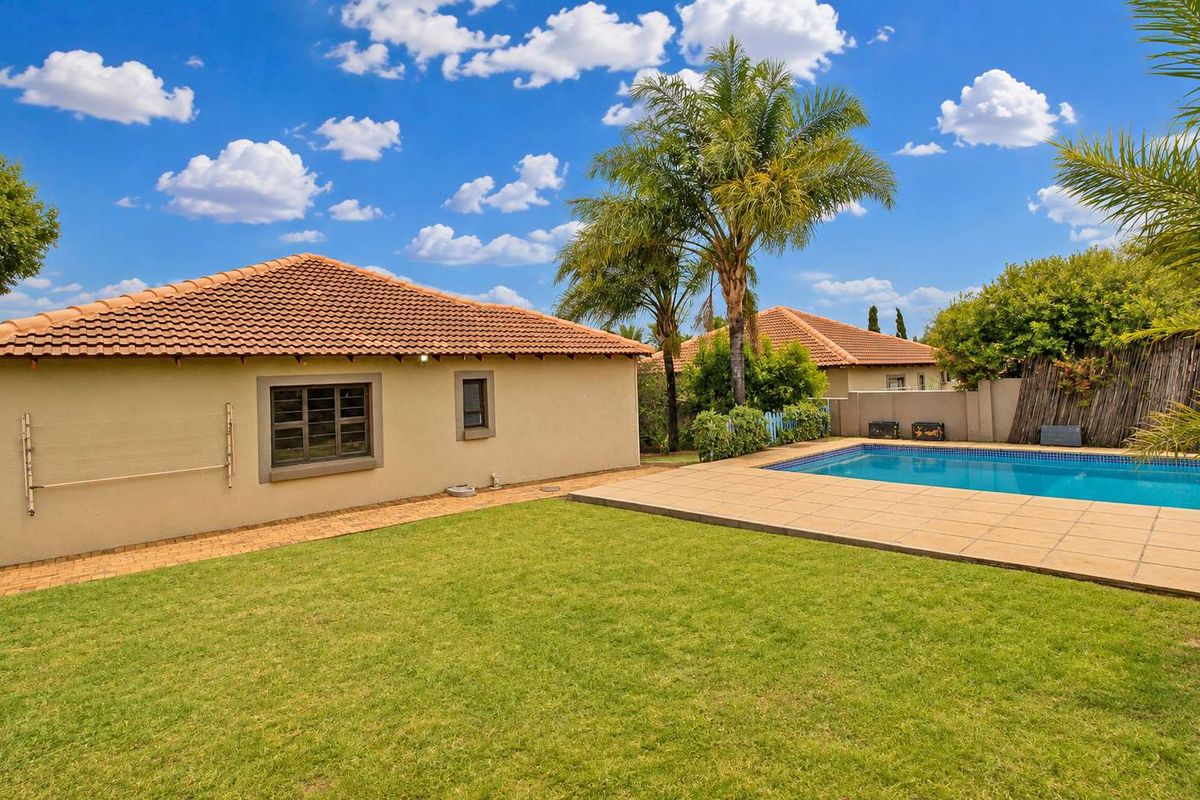 Rear exterior view of the townhouse featuring a private swimming pool, paved patio area, and a well-maintained lawn.