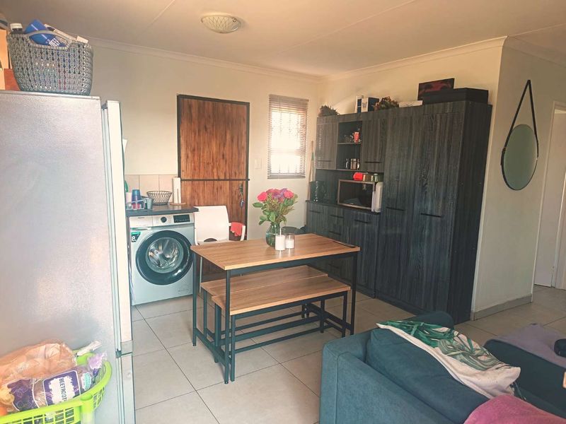 Open-plan living area featuring tiled flooring, built-in cabinetry, and integrated laundry facilities, providing a functional and versatile space.