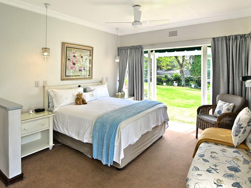 Spacious bedroom featuring carpet flooring, a ceiling fan, and large sliding glass doors providing direct access to the garden.