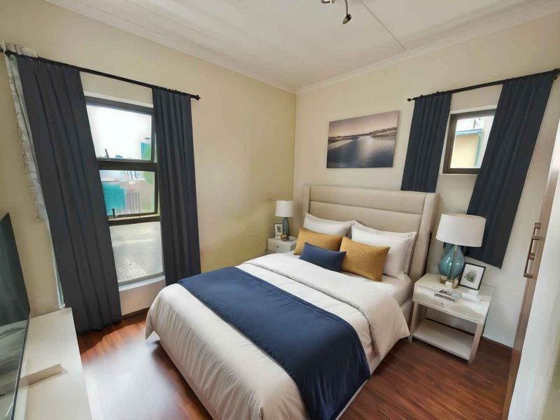 A well-maintained bedroom featuring laminate flooring, coved ceilings, and dual casement windows, providing a comfortable and functional living space.