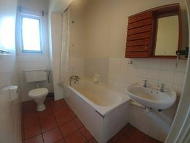 A functional bathroom featuring a bathtub, wall-mounted basin, and toilet with tiled flooring and wall finishes.