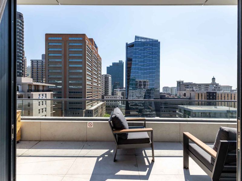Modern balcony featuring a sleek glass balustrade and tiled flooring, offering expansive views of the surrounding city skyline.