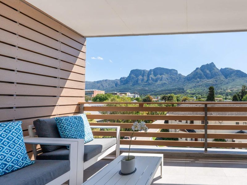 A modern covered balcony featuring timber-look cladding and a horizontal slat balustrade, offering expansive mountain views.