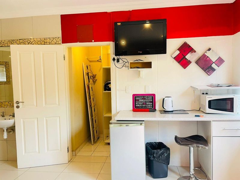 A compact kitchenette area featuring built-in cabinetry, a countertop, and tiled flooring, with an adjacent small storage or utility closet.