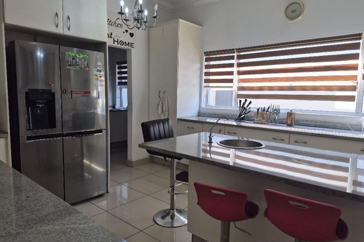A functional kitchen featuring granite countertops, built-in cabinetry, tiled flooring, and a central island with an integrated sink.