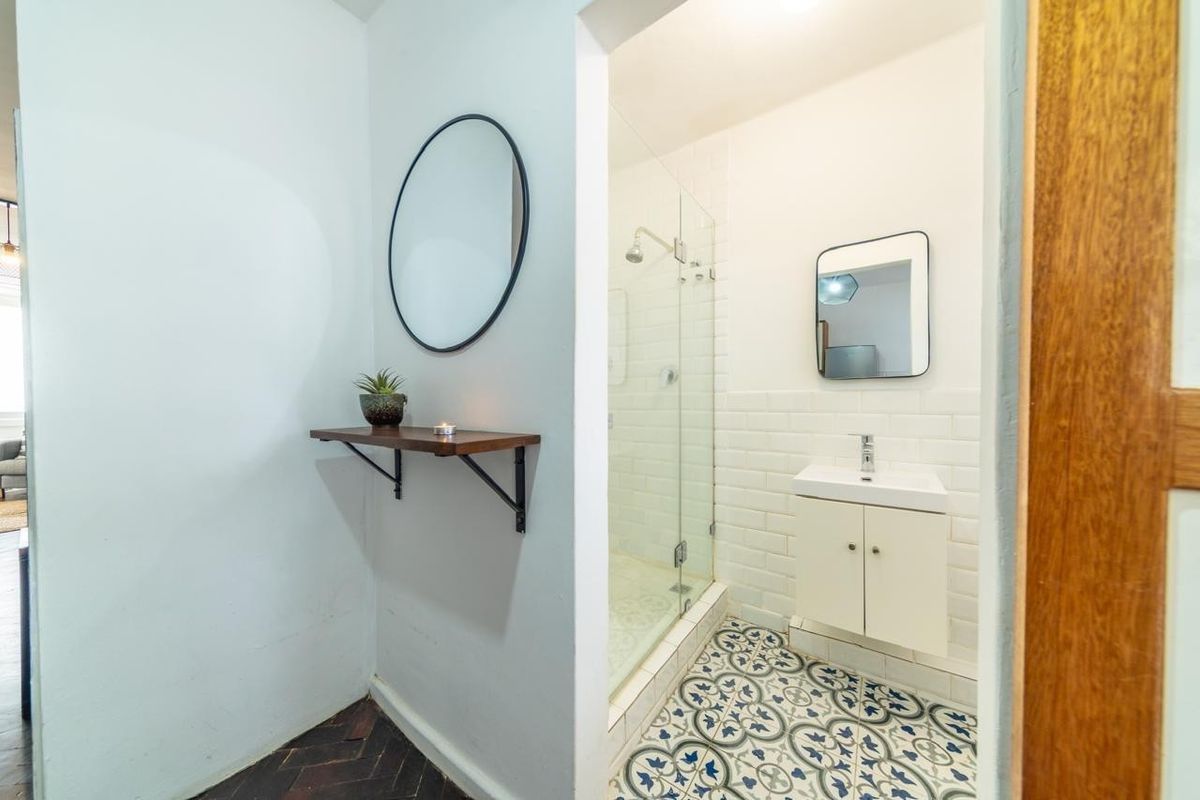A modern bathroom featuring a glass-enclosed shower, white subway wall tiles, and decorative patterned floor tiles with a vanity basin.