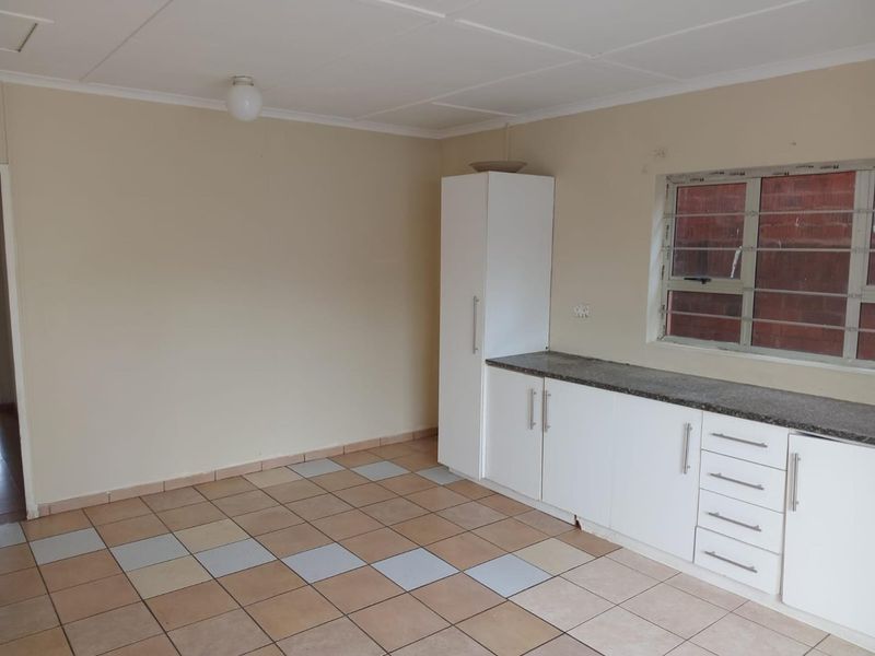 A functional, empty kitchen space featuring white built-in cabinetry, stone countertops, and tiled flooring, ready for personalization.