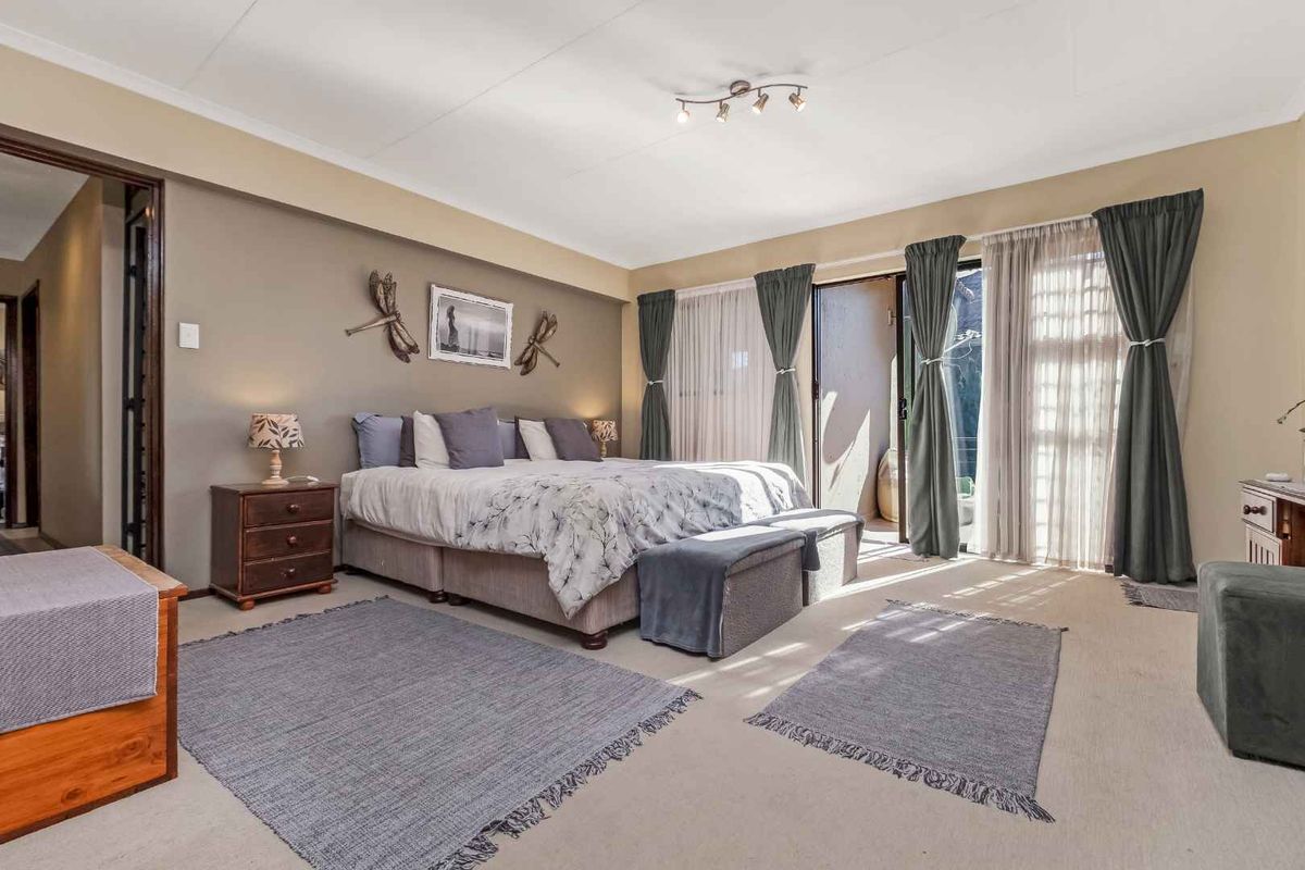 Spacious bedroom featuring neutral carpeting, built-in cupboards, and large sliding glass doors providing direct access to an outdoor patio area.