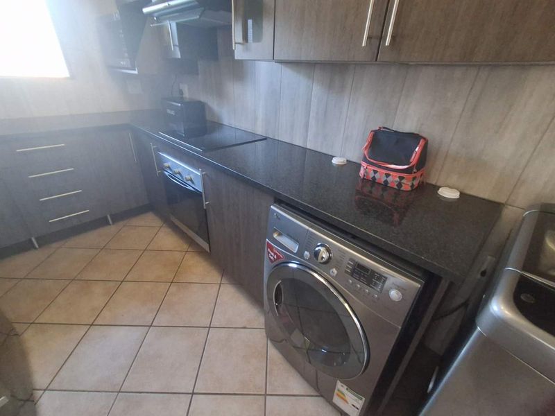 A functional kitchen featuring dark wood-look cabinetry, granite countertops, built-in oven and hob, and tiled flooring.