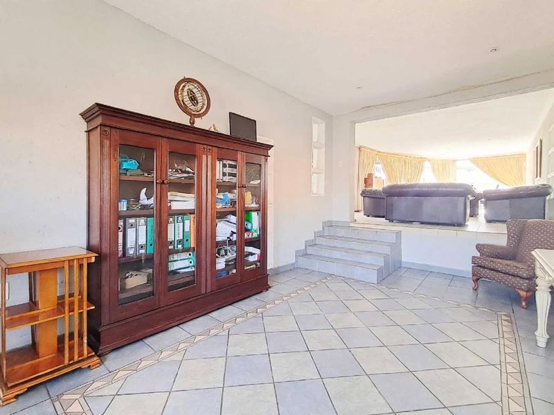 Spacious living area featuring tiled flooring and a raised platform with steps leading to an adjacent lounge space.