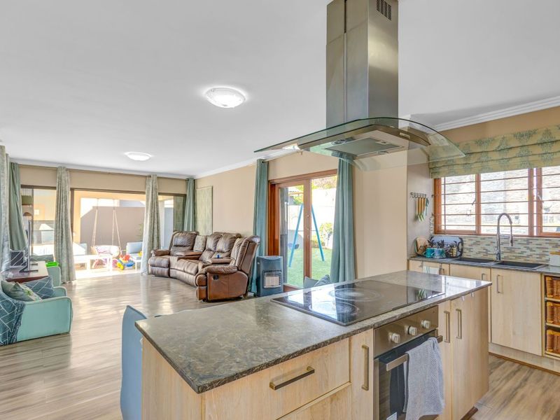Spacious open-plan living area featuring a functional kitchen with island, built-in appliances, and direct access to the outdoor patio through sliding glass doors.