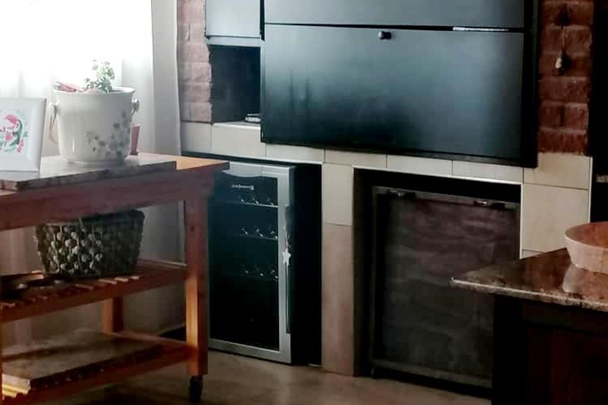 Indoor entertainment area featuring a built-in braai fireplace with brick surround and tiled flooring.