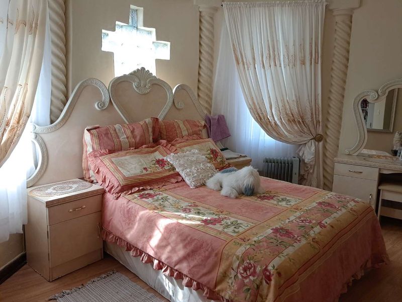 A bedroom featuring decorative columns, a unique feature window, and laminate flooring, offering a distinct architectural style.