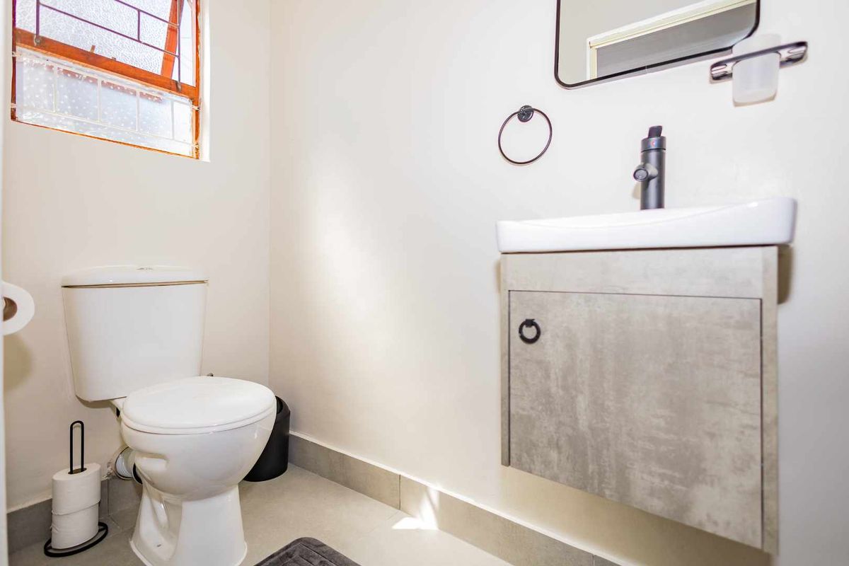 A clean and functional bathroom featuring a modern wall-mounted vanity with a basin, a toilet, and a window providing natural light.