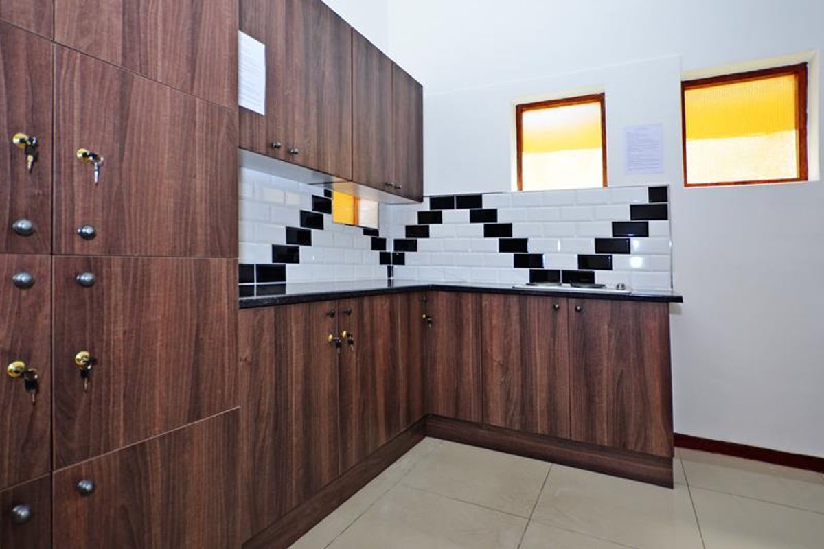 A functional kitchen area featuring dark wood-grain cabinetry, a contrasting black and white subway tile backsplash, granite countertops, and built-in hob.