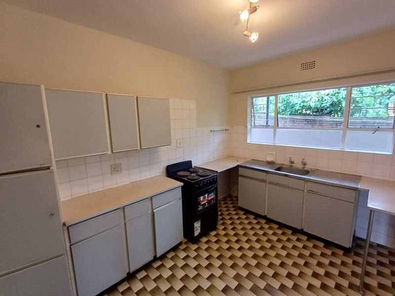 A functional kitchen featuring built-in cabinetry, a stainless steel sink, and a freestanding stove, offering a blank canvas for modern renovation and design updates.
