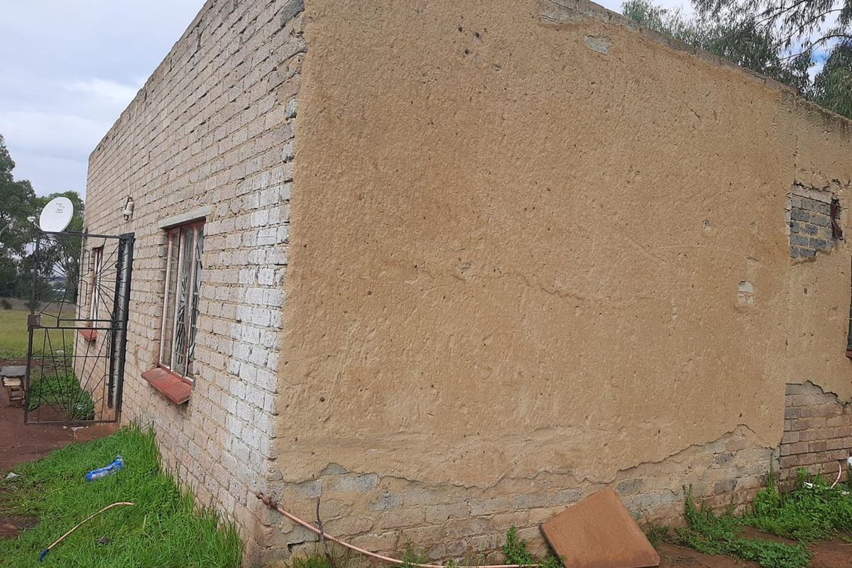 Exterior view of a small holding structure showing brick and plastered walls with visible signs of weathering and maintenance requirements.
