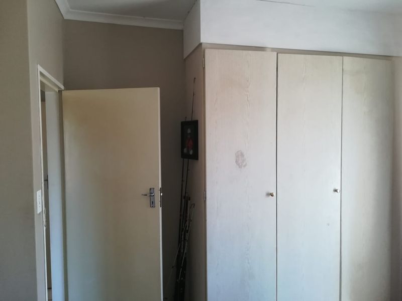 A bedroom interior featuring built-in cupboards with a light wood finish and neutral wall tones, requiring minor cosmetic updates.